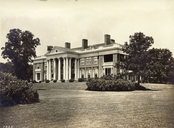 Exterior view of the south face of Wadsworth Hall. A flag flies from the pediment. A large lawn with shrubs and trees is in the foreground.