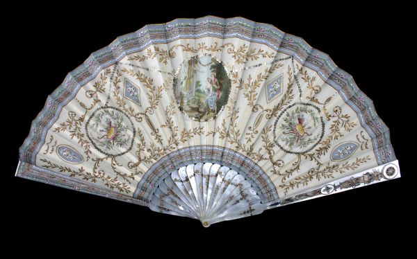 Fan made in 1900-1915 by Duvelleroy, was crafted of Paris silk, mother-of-pearl, paint and sequins. It features an image of lovers looking at a statue of the Greek love goddess, Aphrodite.