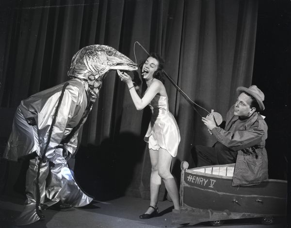 Members of the Wisconsin Idea Theater Group in costume, one man posing dressed as a fisherman, a woman as a bathing beauty, and another person as a giant fish.