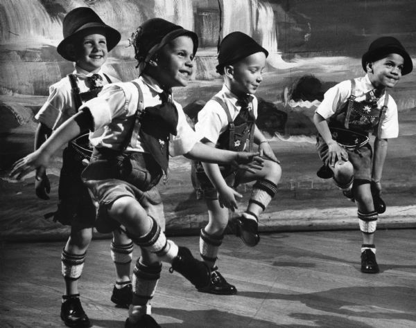 Group of four boys in Bavarian costume performing a Bavarian folk dance.