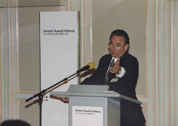 Wisconsin Governor Tommy G. Thompson gestures while speaking from a podium while promoting Midwestern businesses in Germany.