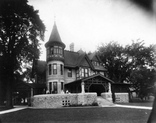 Exterior view of the Babcock home, a Queen Anne style structure at 537 E. Wisconsin Avenue. The family stands on the porch.