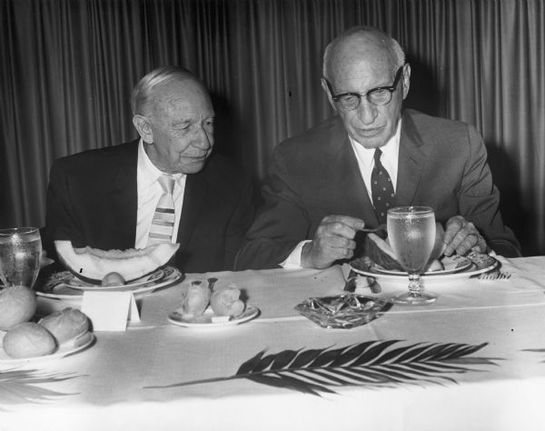 Rabbi Morris Lazaron is seated next to Lessing Rosenwald at a formal dinner. There is a palm leaf on the table.
