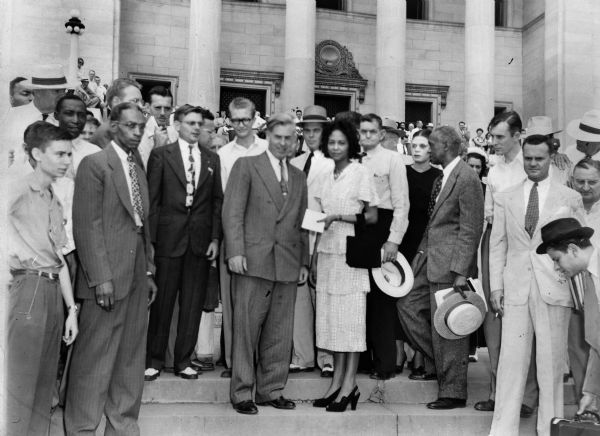 A candid group portrait of well-dressed people featuring Henry Wallace and Daisy Bates. L.C. Bates stands to the left of Daisy.
