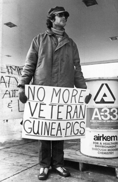 A Vietnam veteran holds a hand-lettered sign that reads, "No More Veteran Guinea Pigs".