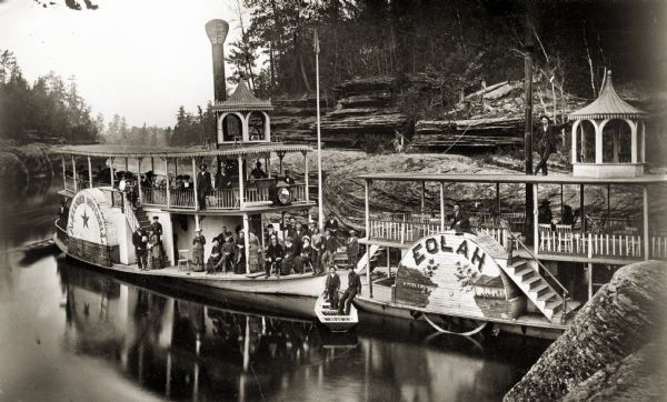 Excursion boats at the Wisconsin Dells. Boats <i>Eolah</i> and <i>Alexander Mitchell</i> at mooring, with distinctive Dells rock formations in the background and passengers on board.
