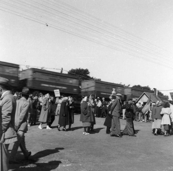 Workers on strike march with signs near a railroad crossing.