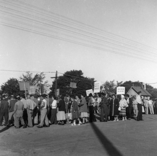 A group of striking workers march together carrying signs near a railroad crossing.
