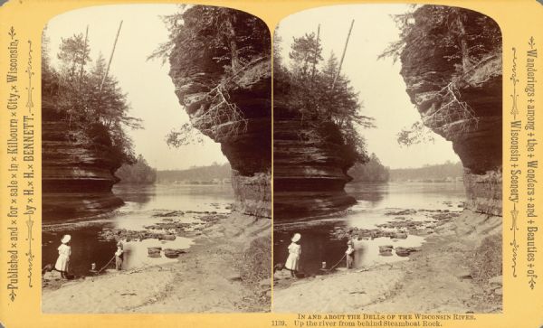 View from behind Steamboat Rock of two children playing at the edge of the Wisconsin River. Huge rock formations are in the background. Text at left: "A Trip Through the Dells of the Wisconsin. "Text at right: "Wanderings Among the Wonders and Beauties of Wisconsin Scenery."