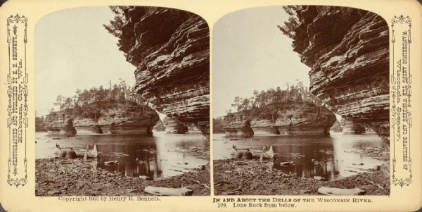A few from a shoreline of the formation Lone Rock on the Wisconsin River. A canoe is in the water, and another formation is in the background. Text at right: "Wanderings Among the Wonders and Beauties of Wisconsin Scenery."