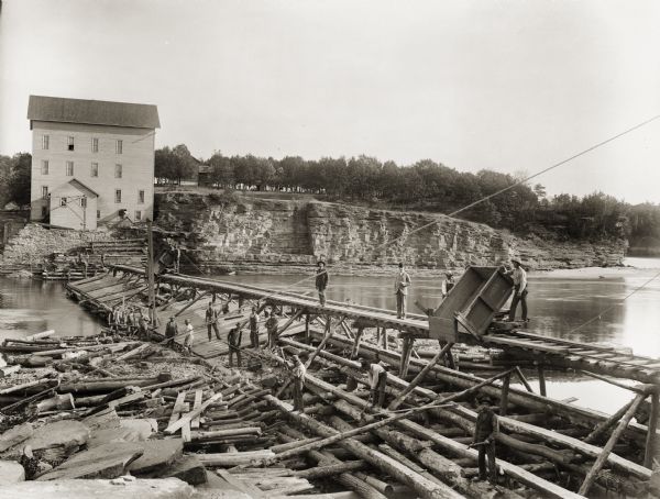 Munger's Mill and dam, with men standing on and around the dam.