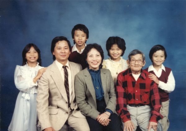 A studio portrait of the Nguyen family. From left to right are: Thuy, Trong (father), Minh, Hong (mother), Mary, Kim (grandfather), and Charlie.