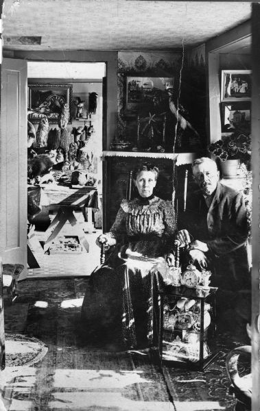 Paul A. Seifert, and unidentified woman seated indoors. He lived in Richland Center, now known as Gotham, Wisconsin. He was a taxidermist and curio collector. Paul A. Seifert was born June 11, 1846, and died August 18, 1921. A folk artist, Paul Seifert painted a number of Wisconsin farms in and around Richland County, circa 1885.