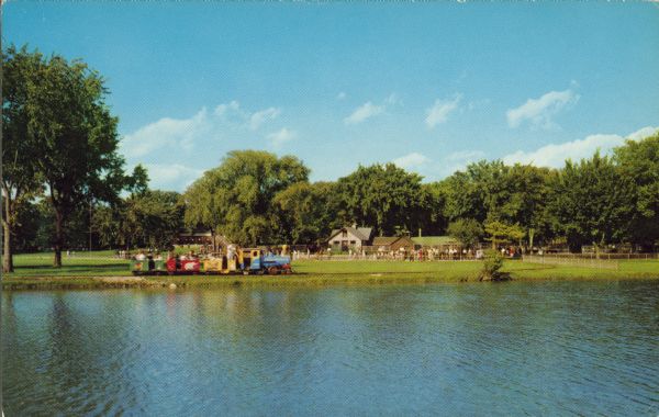 View across water towards the kiddie train at Vilas Park Zoo (Henry Vilas Zoo). The train was donated by the Madison Lions Club and operated from 1953-1968.