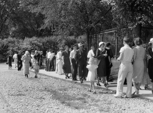 Visitors strolling at Vilas Park Zoo (Henry Vilas Zoo), some looking at the animal cages.  This picture by Harold Hone was one of many Wisconsin images made during the 1930s to illustrate "Wisconsin: A Guide to the Badger State."