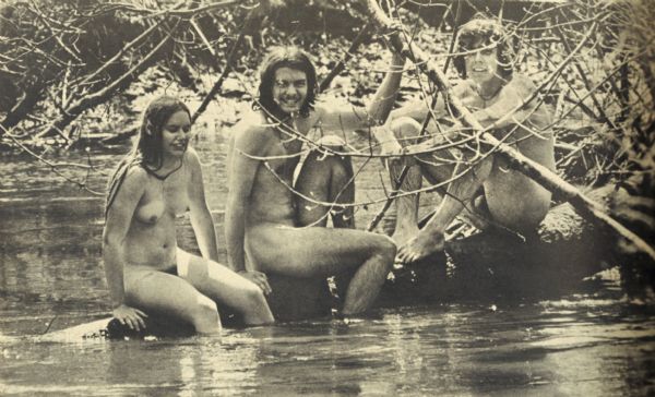 Steve Landaal and two friends sit on a log over a creek at the Sound Storm rock festival. They are enjoying nude sunbathing.