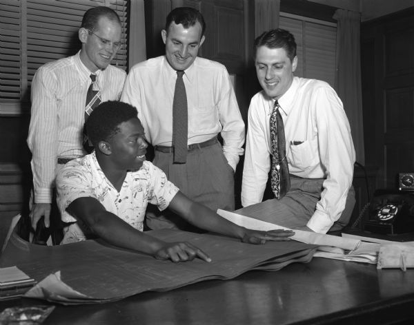 Curlee Seals, Jr. discussing plans for his 1949 Soap Box Derby racer with three members of the Madison Junior Chamber of Commerce, Curlee's sponsor for the race. Seated is Curlee, son of Curlee and Rosetta Seals, 1912 Baird Street. Standing: William D. McNeil, Jaycee board member; Hal Frye, vice president; and Lee A. Baron, president.