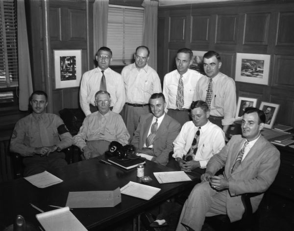 Group portrait of the officials for the 1949 Soap Box Derby. Left to right, seated: Sgt. Ed Roman, of the Marine recruiting station; Ralph Hult, president of the Capital Garage; Elmer Nielsen, Dane district Boy Scout commissioner; and Hal Frye, youth activities director of the Madison Junior Chamber of Commerce. Standing, left to right:  Glen "Pat " Holmes, city recreation director; Jim Brophy, assistant street commissioner, James G. Marshall, park commissioner; and  Capt. J. Homer Elder, city traffic bureau.