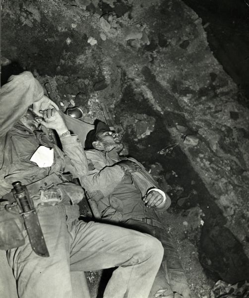 Wounded men are laying in a foxhole in Iwo Jima waiting to be moved to another location.