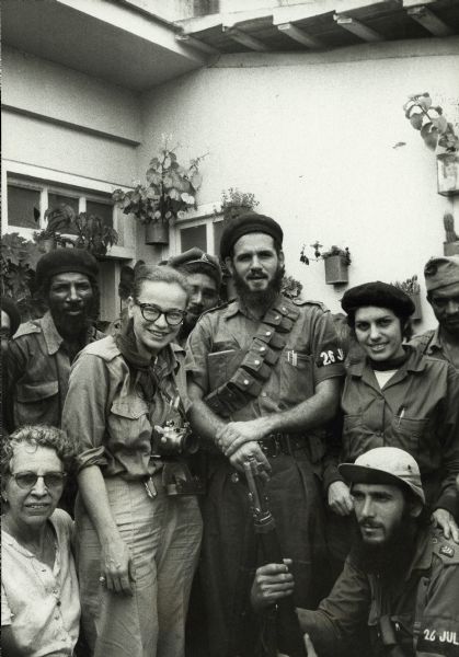 Dickey Chapelle posing in Cuba with Major Antonio Lusson, and a group of male and female soldiers.