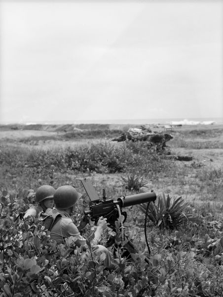 Two soldiers huddle behind a 30mm machine gun. Part of a series of images made by Chapelle during World War II in the Pacific Ocean region, including images of Iwo Jima, Okinawa, and Guam.