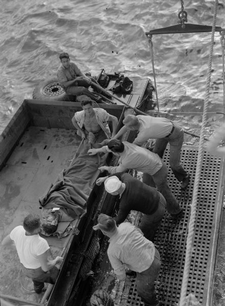 Overhead view of men loading a wounded soldier onto a hospital ship.