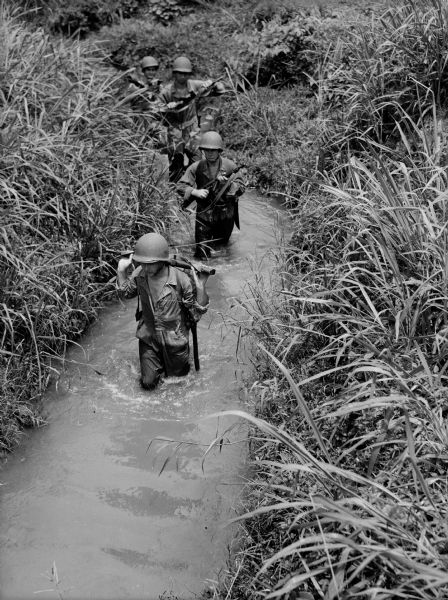 Soldiers on patrol ford a stream in Panama.
