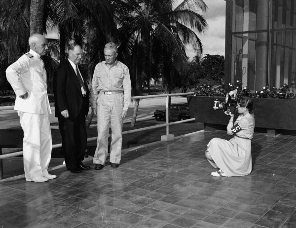 A young woman takes a photograph of Admiral Van Hook, Secretary Knox, and General Frank Andrews at Coco Solo Submarine Base Officer's Club.