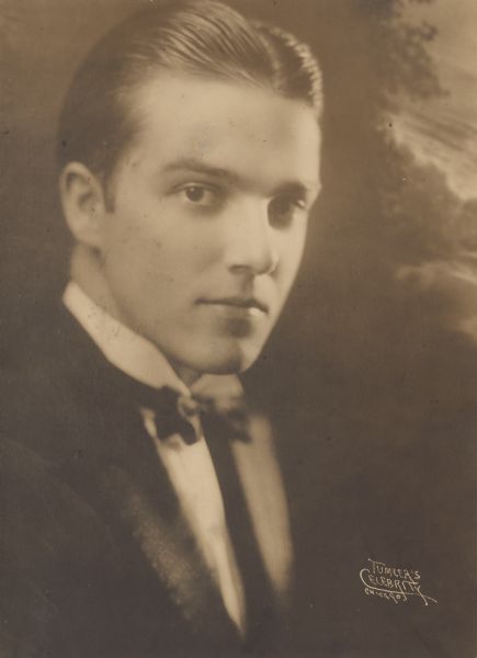 A handsome studio portrait in front of a painted backdrop of Leo Kehl wearing a suit and bowtie.
