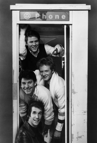 The cast of the television show "Happy Days" pose in a telephone booth. From top to bottom are Ron Howard, Donny Most, Anson Williams, and Henry Winkler.