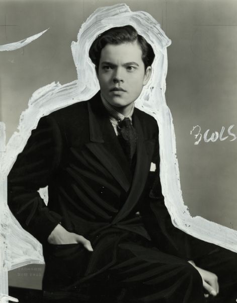 Portrait of a young Orson Wells wearing a suit, heavily retouched to isolate him from the background.