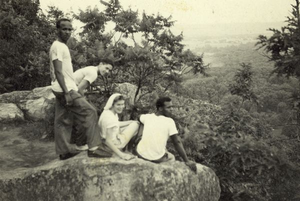 Lewis Arms and friends perch on a bluff overlooking Devil's Lake. From left to right are: Arms, Eddie Elvord (Alvord?), Mary Rogers, and George Green (Greene).