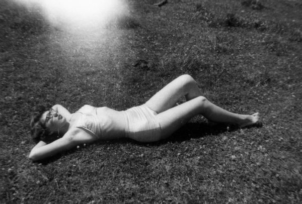 Carol Commack Banks lays on the grass in her bathing suit, relaxing in the sun.