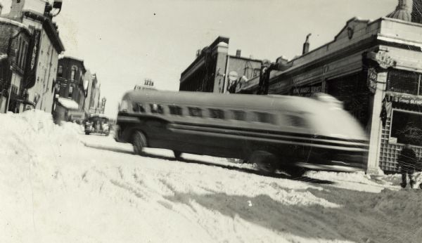 A Greyhound bus turning onto a snowy street. Lewis Arms, a Greyhound employee, wrote this on the back of the photograph, "I would like to have one of these to make into a camper motor home."