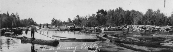 Loggers known as "river pigs" round up stray logs with pikes and peaveys at Place's Rapids.