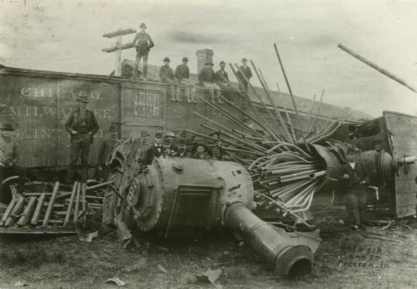 Men pose around the remains of runaway train Engine No. 80 after it crashed and the boiler exploded on the Chicago, Milwaukee, and St. Paul Railway.
