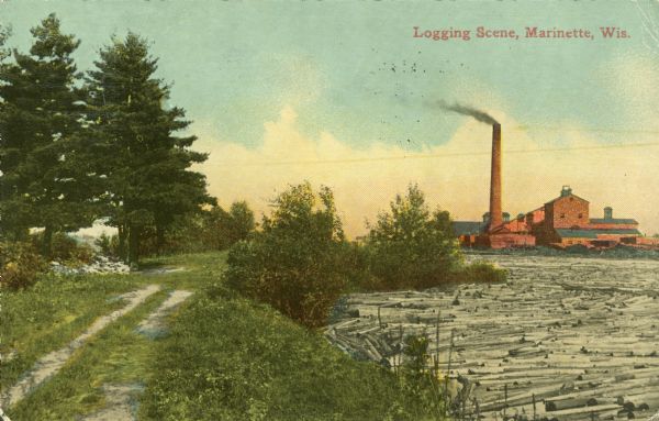 Colorized view of a river full of logs, and a smokestack and factory in the distance. On the left is a dirt road and trees. Caption reads: "Logging Scene, Marinette, Wis."