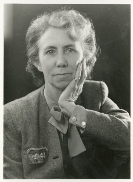 Quarter-length studio portrait of Miriam Bennett wearing a blazer and brooch.