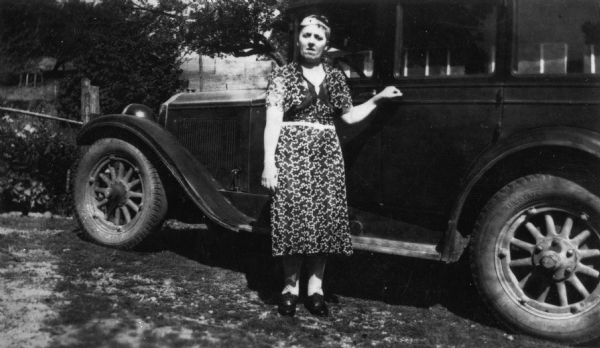 Neva Schultz of the Dane County Hospital and Home poses next to an automobile.