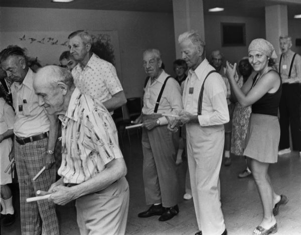 A music therapist (wearing a scarf on her head) leads a group of elderly residents of the Dane County Home in a music therapy session.