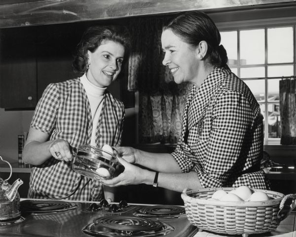 Ellen Proxmire and an unidentified woman shown in a kitchen cooking.