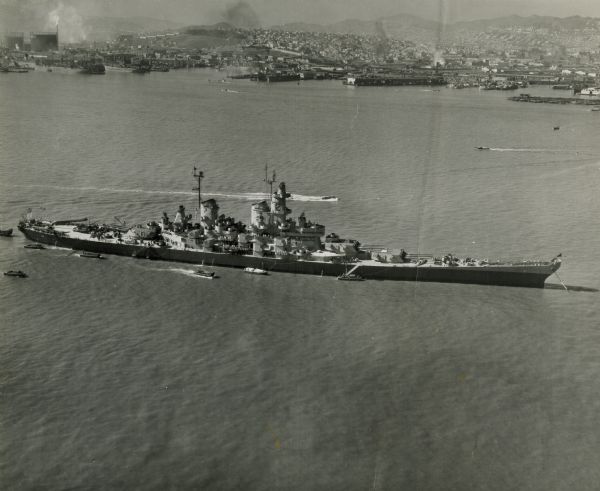Aerial view of U.S.S. <i>Wisconsin</i> (BB-64) in San Francisco Bay. Several boats can be seen in the water near the ship and San Francisco is visible in the background.