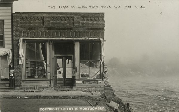 View of Monsos Brothers Grocery & Crockery after most of the building was washed away by the flooding Black River. High, rushing water can be seen on the right. There is an ad for Lawrence Barrett Cigars on the building next door, a Copenhagen (tobacco) sign, a Tom Moore Cigar (10¢) ad, and a Prince George Cigar (5¢) ad on the Monson Bros. building. Caption reads: "The Flood at Black River Falls, Wis."