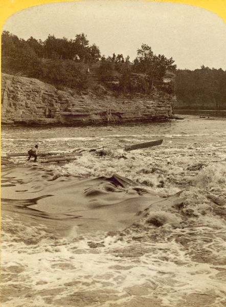 Stereograph of Jim Short steering a raft riding the rough waters of the river.