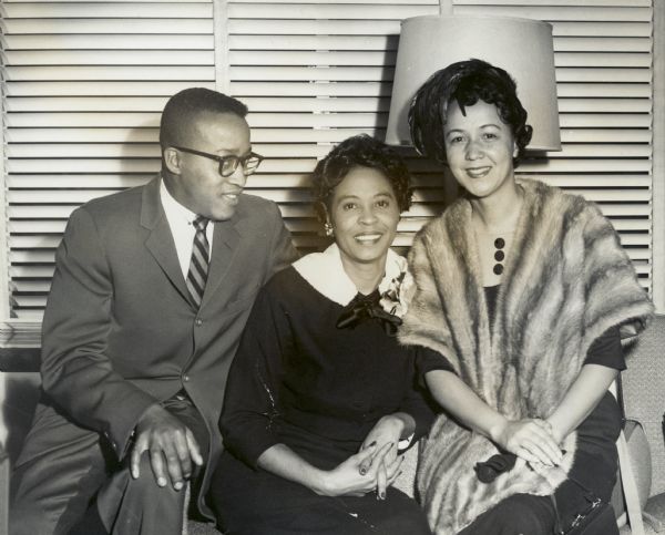 Daisy Bates posed on a sofa between an unidentified man and an unidentified woman who is wearing a fur cape.