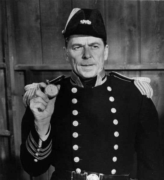 Ronald Reagan stars as Capt. David Farragut in "The Battle of San Francisco Bay," an episode of <i>Death Valley Days</i>. Reagan holds a pocket watch in one hand and wears a naval uniform.