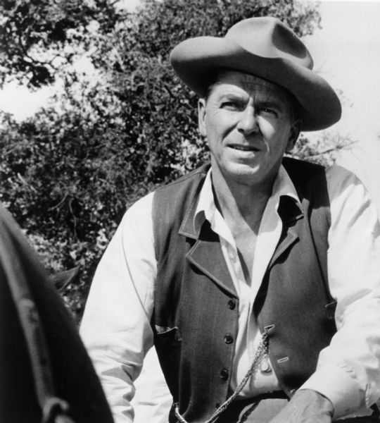 Ronald Reagan sits on a horse in a publicity still for the TV show <i>Death Valley Days</i>.  He wears a hat and a vest with a pocket watch fob attached to it.