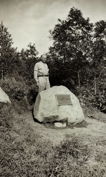 Joe Lucius stands behind a monument rock at Lake St. Croix, at the end of the Portage Trail.