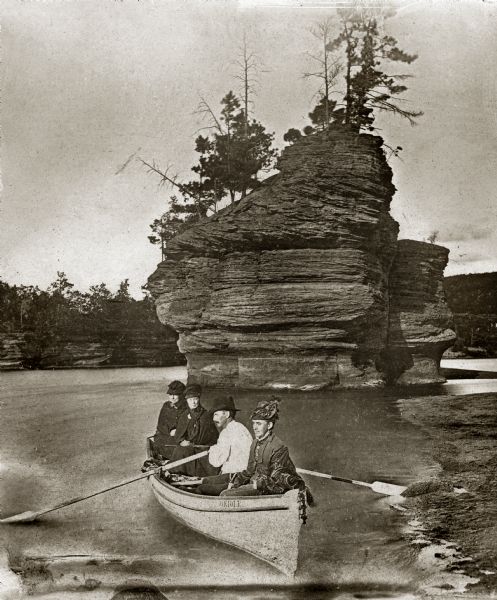 Rowboat (Oriole) with four people in foreground near shoreline, with Sugarbowl in the background.