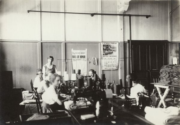 View of young women learning to operate machines in a shirt and overall factory.